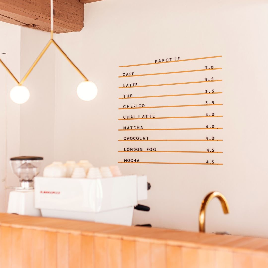 metal menu in brass finish with black letters displaying café menu above wooden counter