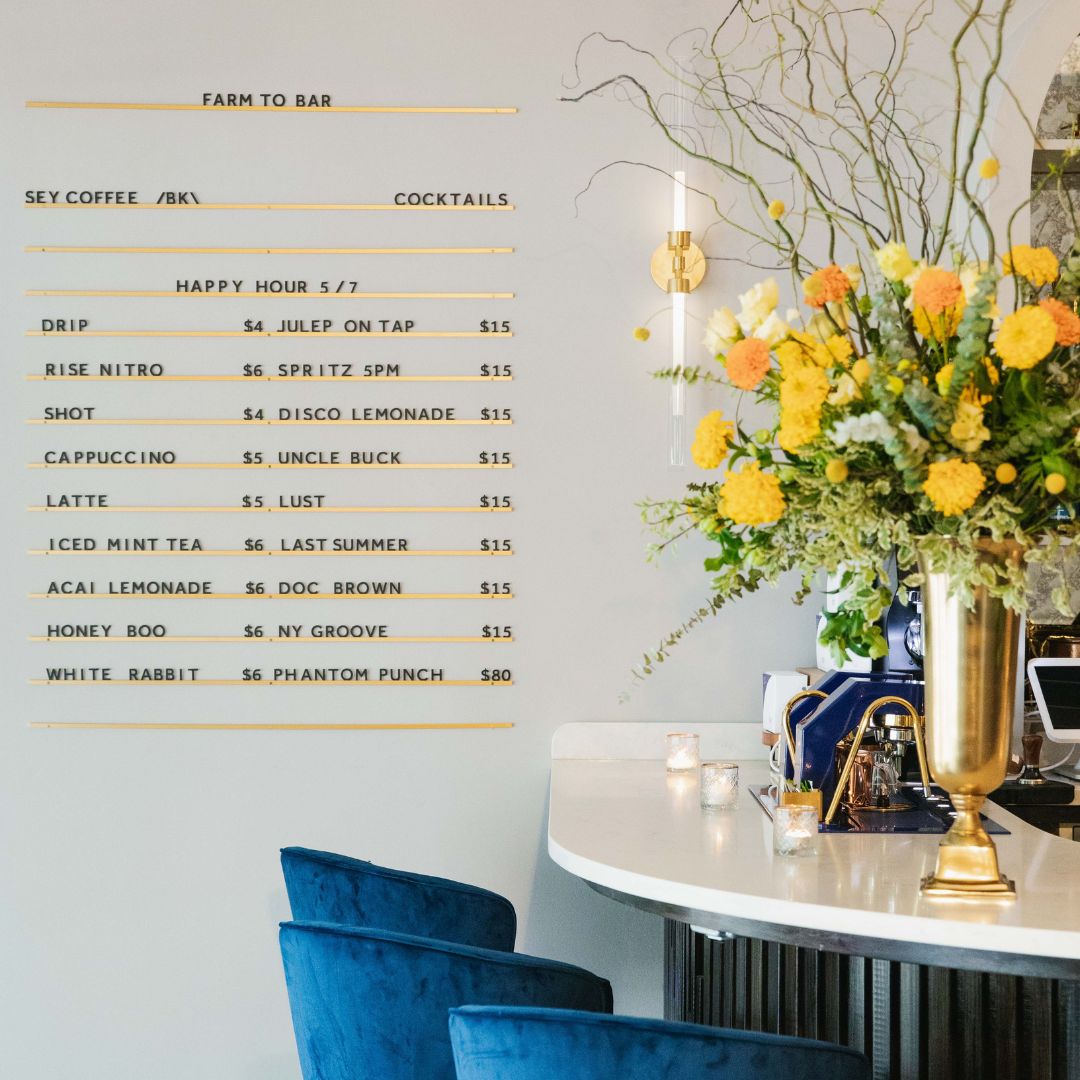 refined Letter Board in a restaurant with black letters on gold finish rails, styled with flowers and blue chairs