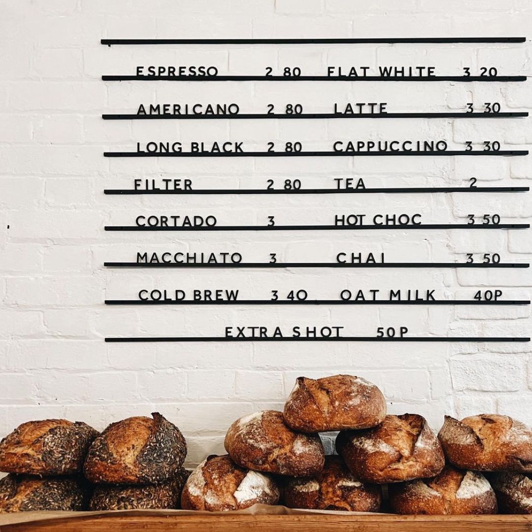 Atelier Letter Board with black rails and black letters with café menu and baked breads on counter underneath