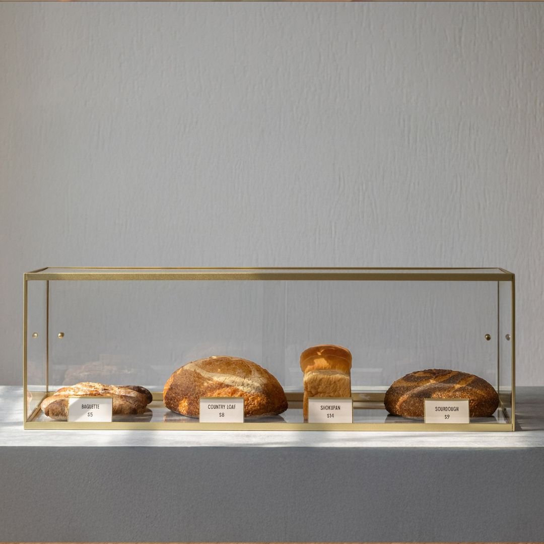 Scratch free acrylic bakery display case with bagels and croissants on display shelf with small white menu signs