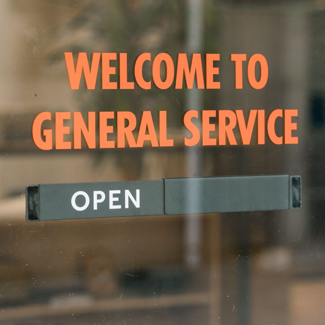 Open Closed shop sign mounted on café window with welcome message on the glass window