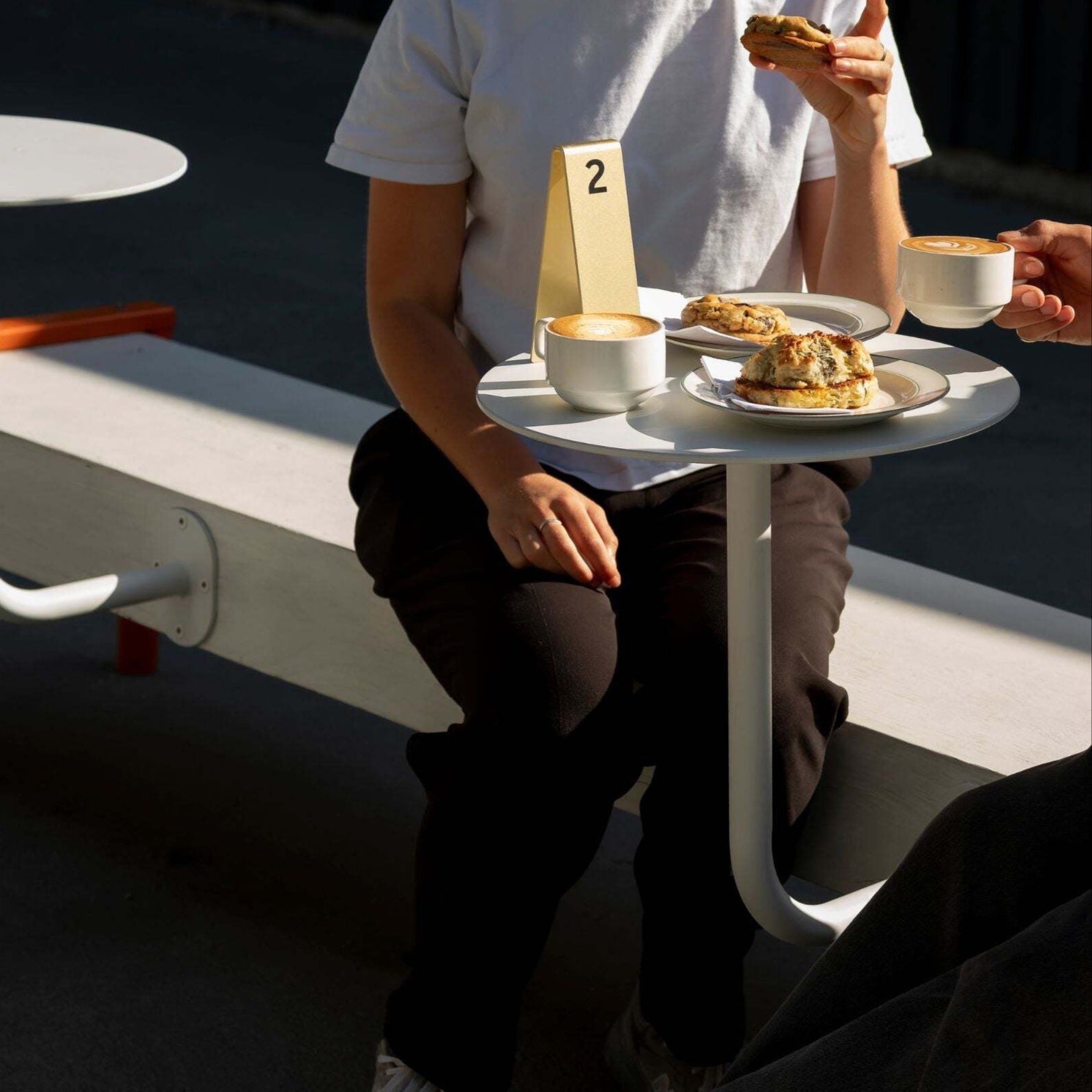 Customer seated at wall-mounted cafe table enjoying drink in outdoor restaurant seating