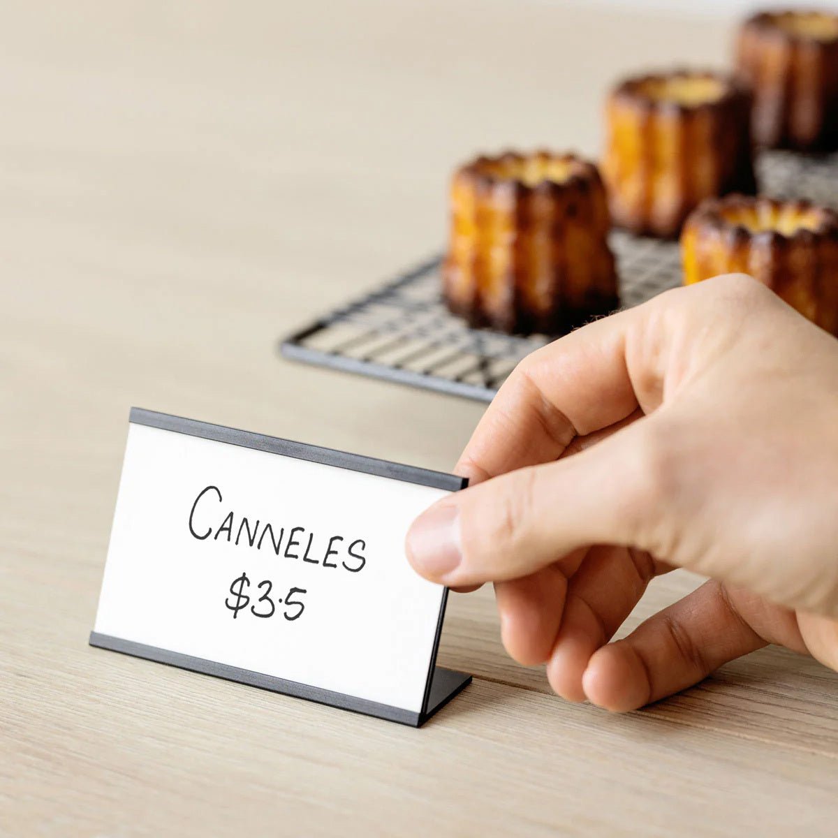 black card counter sign displayed in front of madeleine pastries showing handwritten price