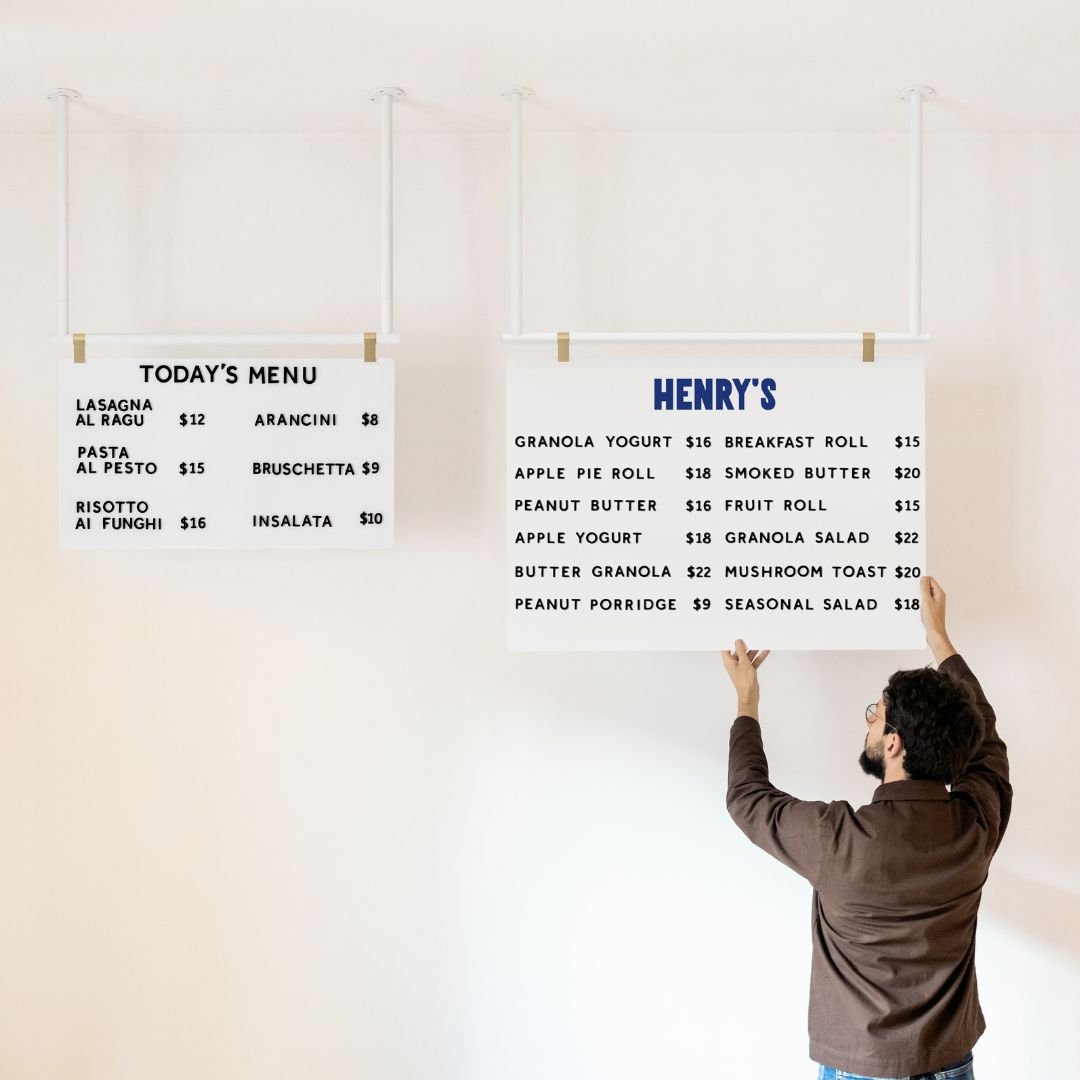 two ceiling menu boards in different sizes side by side, with person holding the larger board