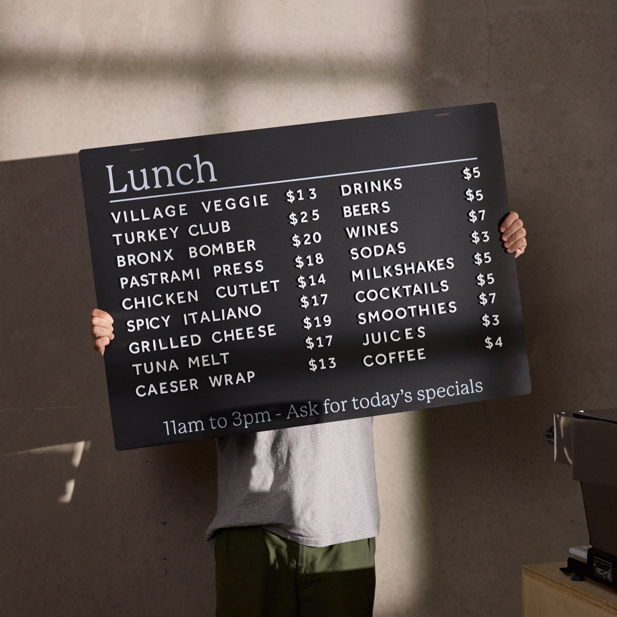 person holding up the board of ceiling menu board in front of them with menu displayed