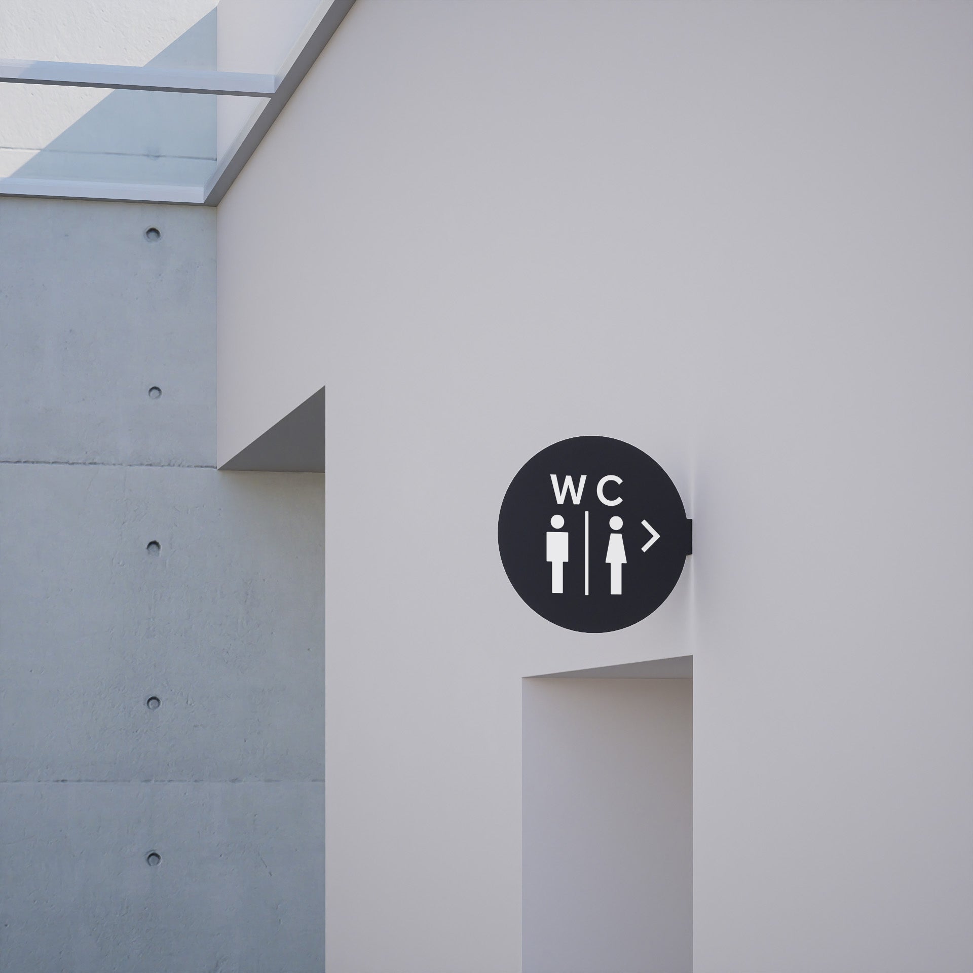 black circle blade sign with toilet decal applied to be a bathroom sign, installed on a wall