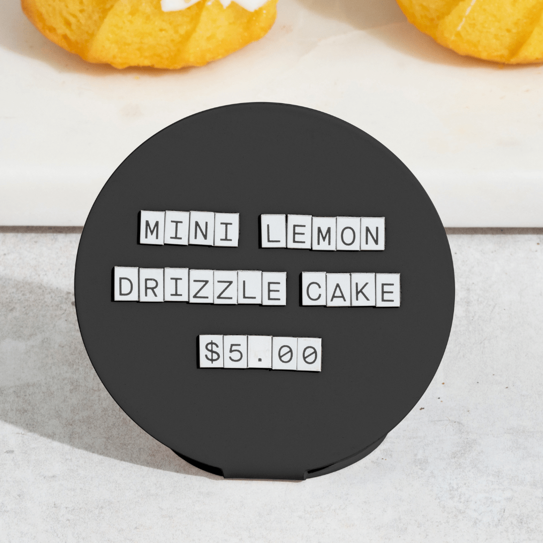 black circle counter sign in front of cakes used for bakery display pricing