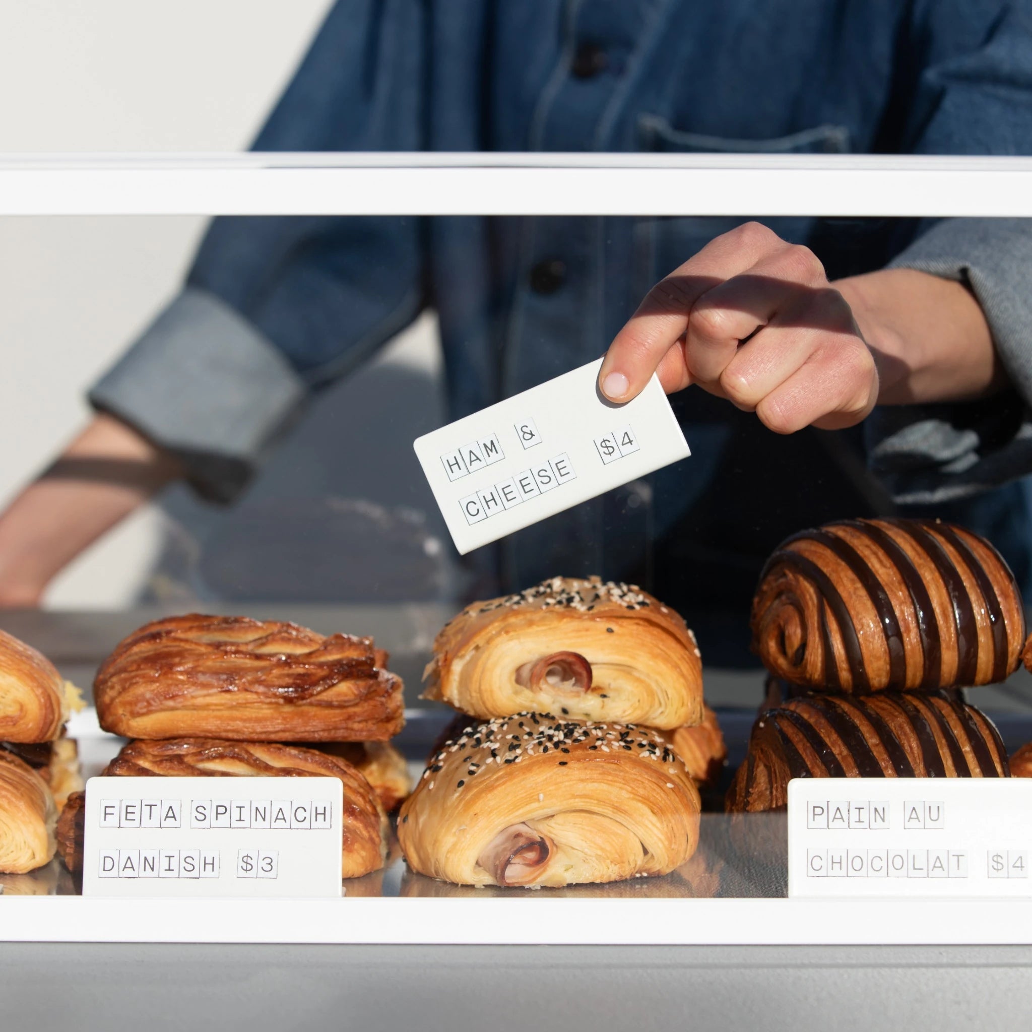 white counter signs used in a bakery display cabinet labelling savoury pastries