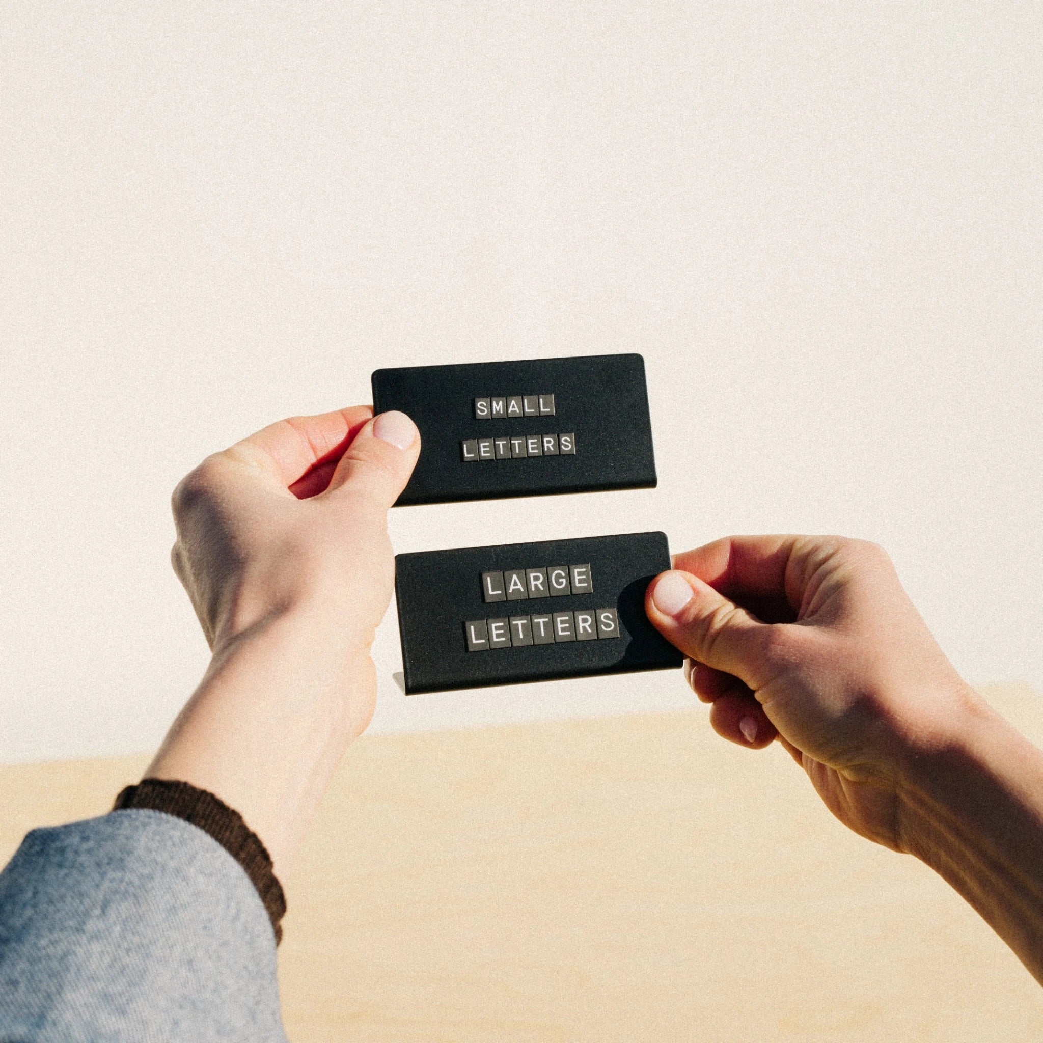 black counter signs with hands being held up displaying small and large letters