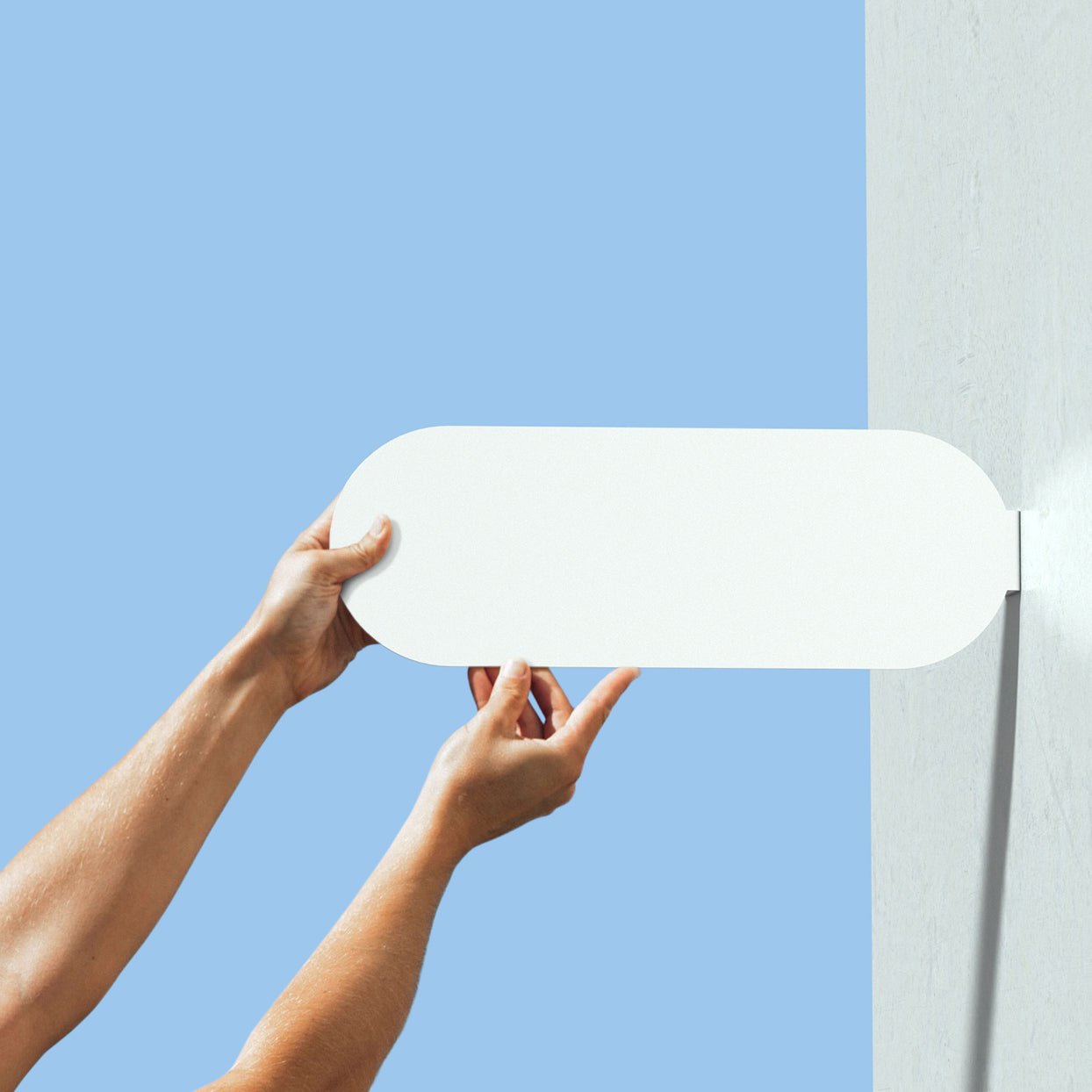 two hands holding up curve pill blade wall sign with no branding