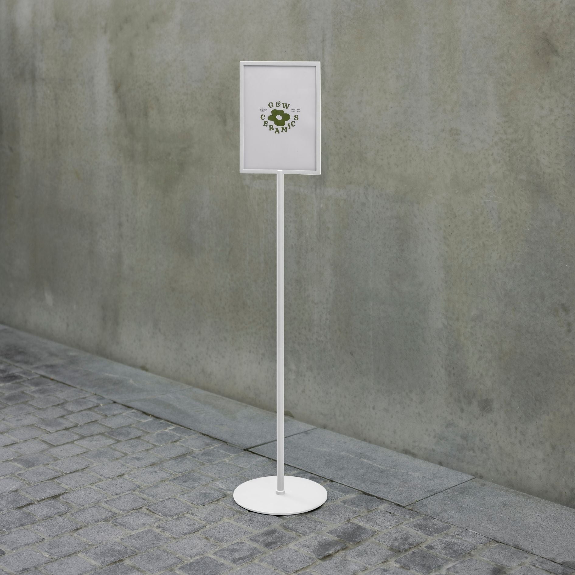 white metal standing sign holder in front of a concrete wall