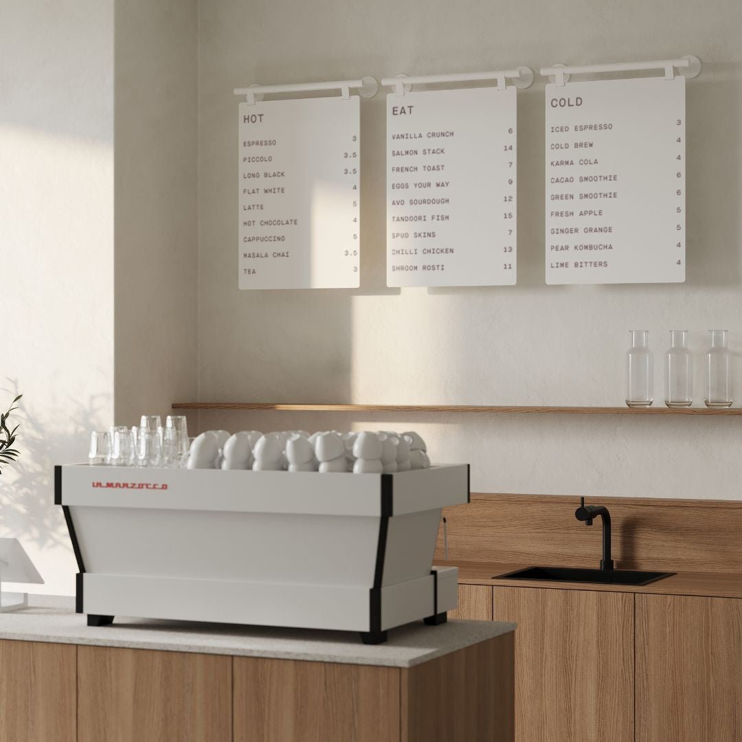 three white hanging menu boards mounted side by side behind a cafe countertop