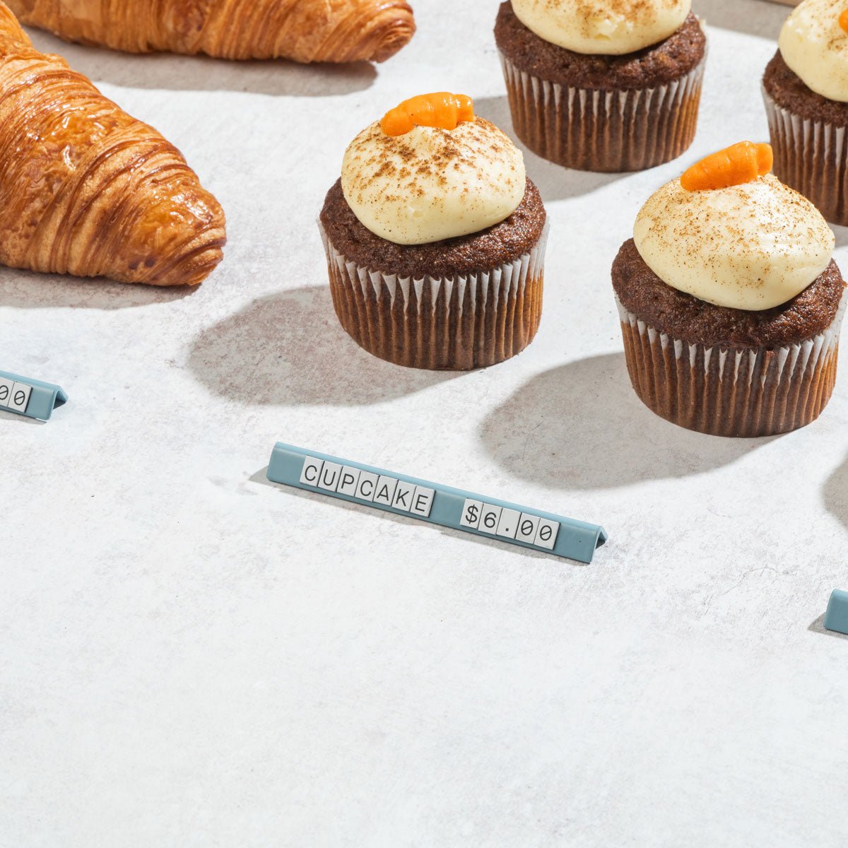 large pricing signs in front of small cakes and pastries