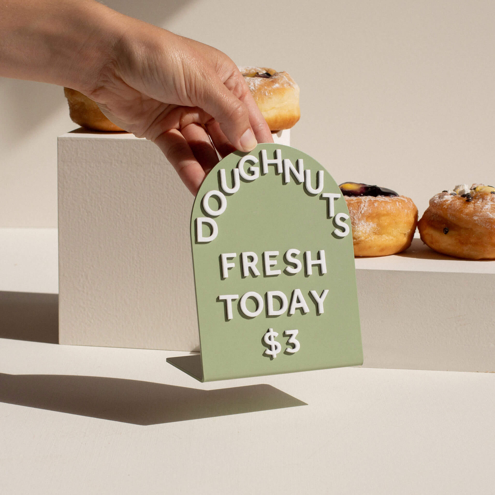 a hand holding a green round table talker counter sign off the table
