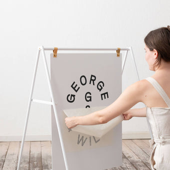 white large sidewalk pavement sign inside a studio with person applying advertising vinyl to the face plate