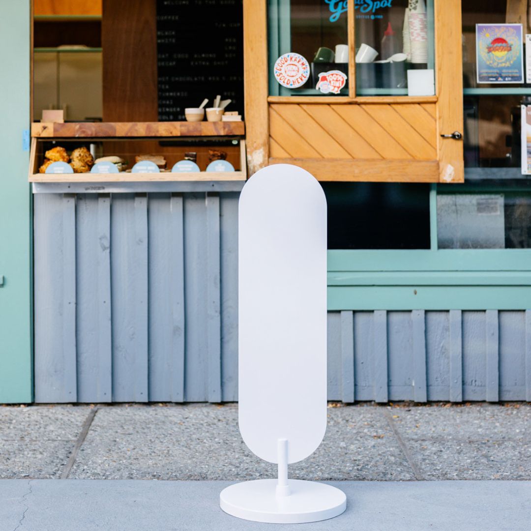 plain white large standing curve sign in front of a coffee shop window