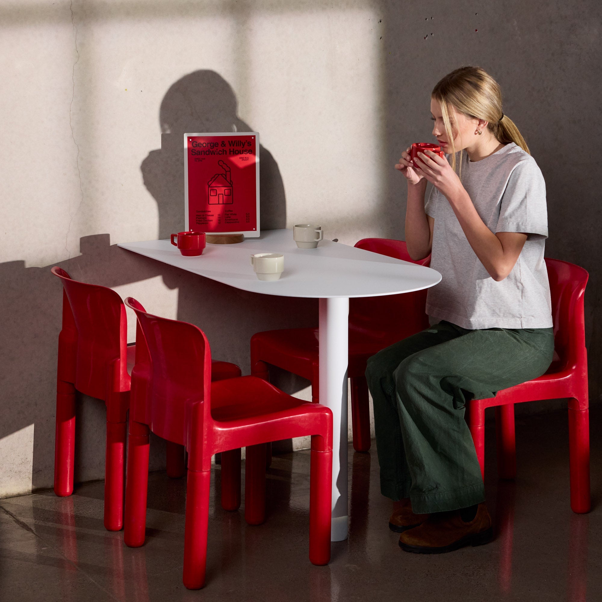 person sitting and drinking coffee at a table hosting a large white table talker with red paper display