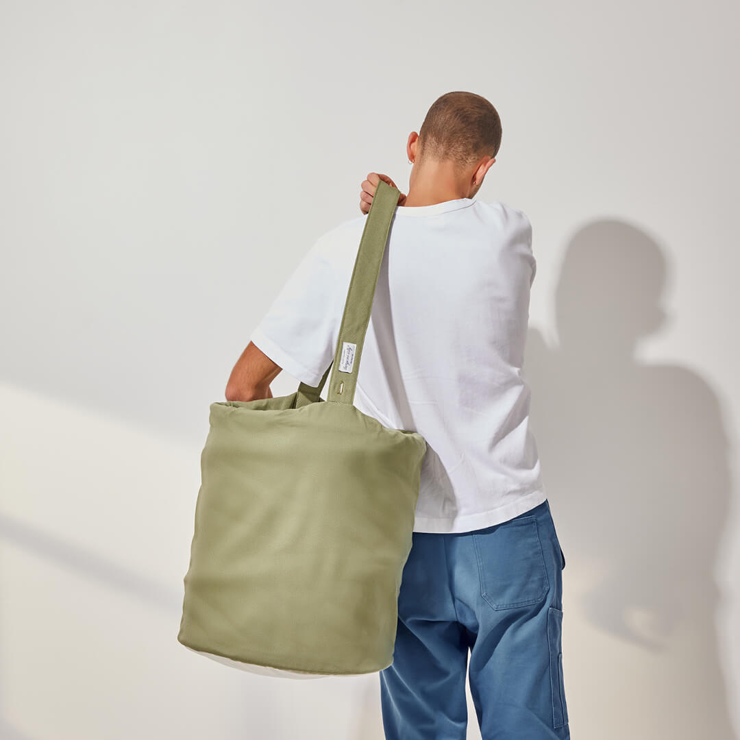 person carrying the laundry basket hamper over their shoulder