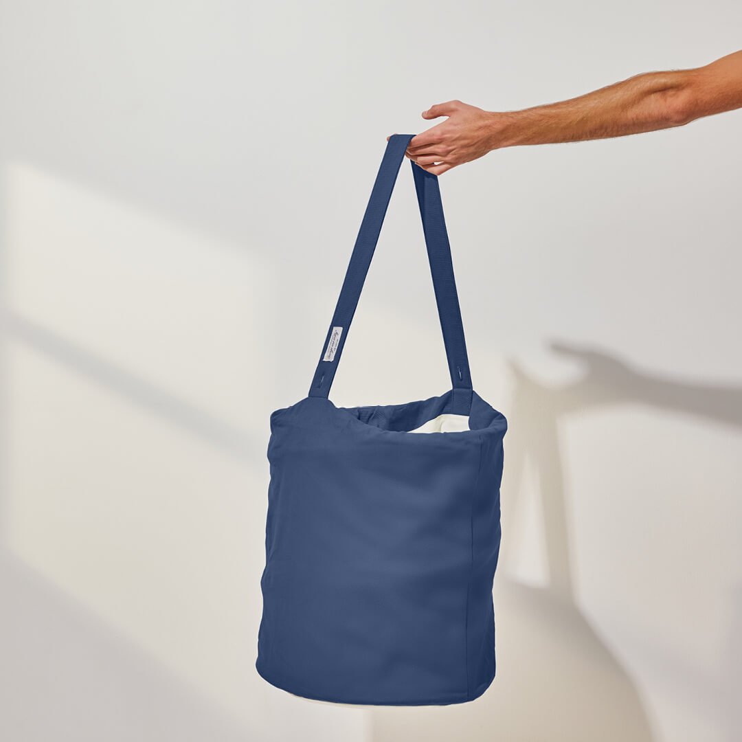 person holding the handle of the laundry hamper in blue
