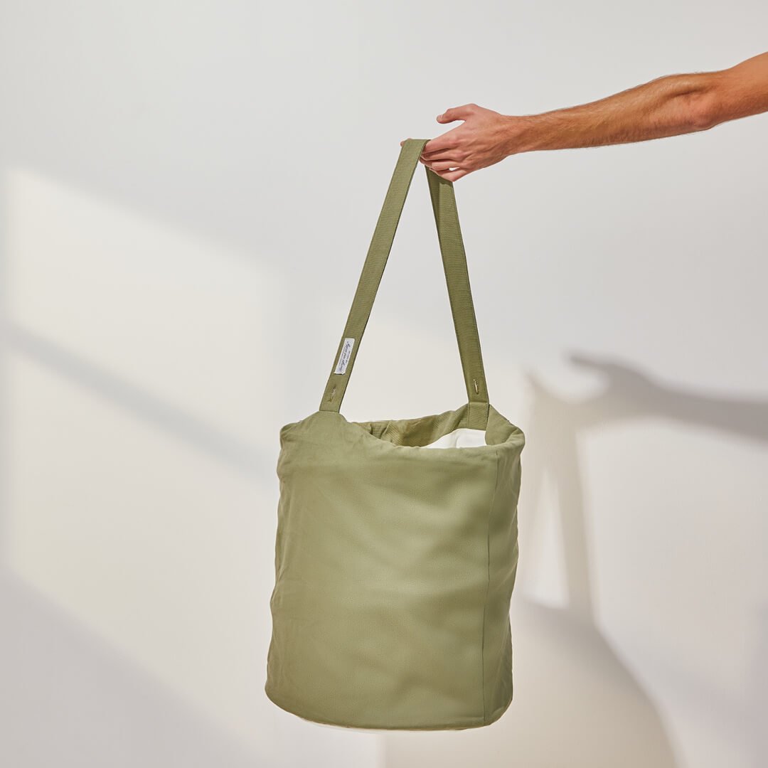 person holding the handle of the laundry hamper in green