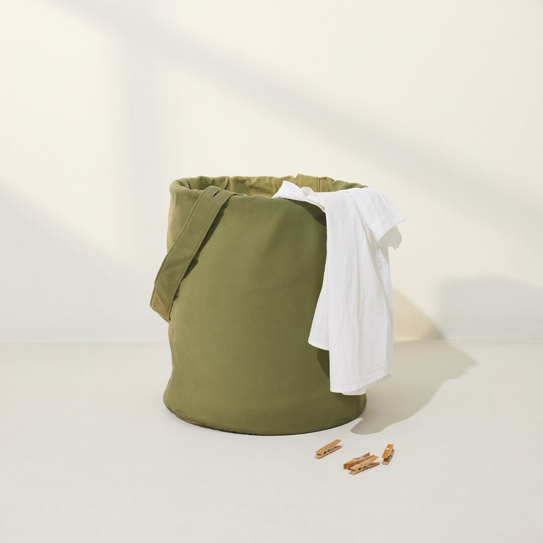 green laundry hamper with tshirt hanging over the top