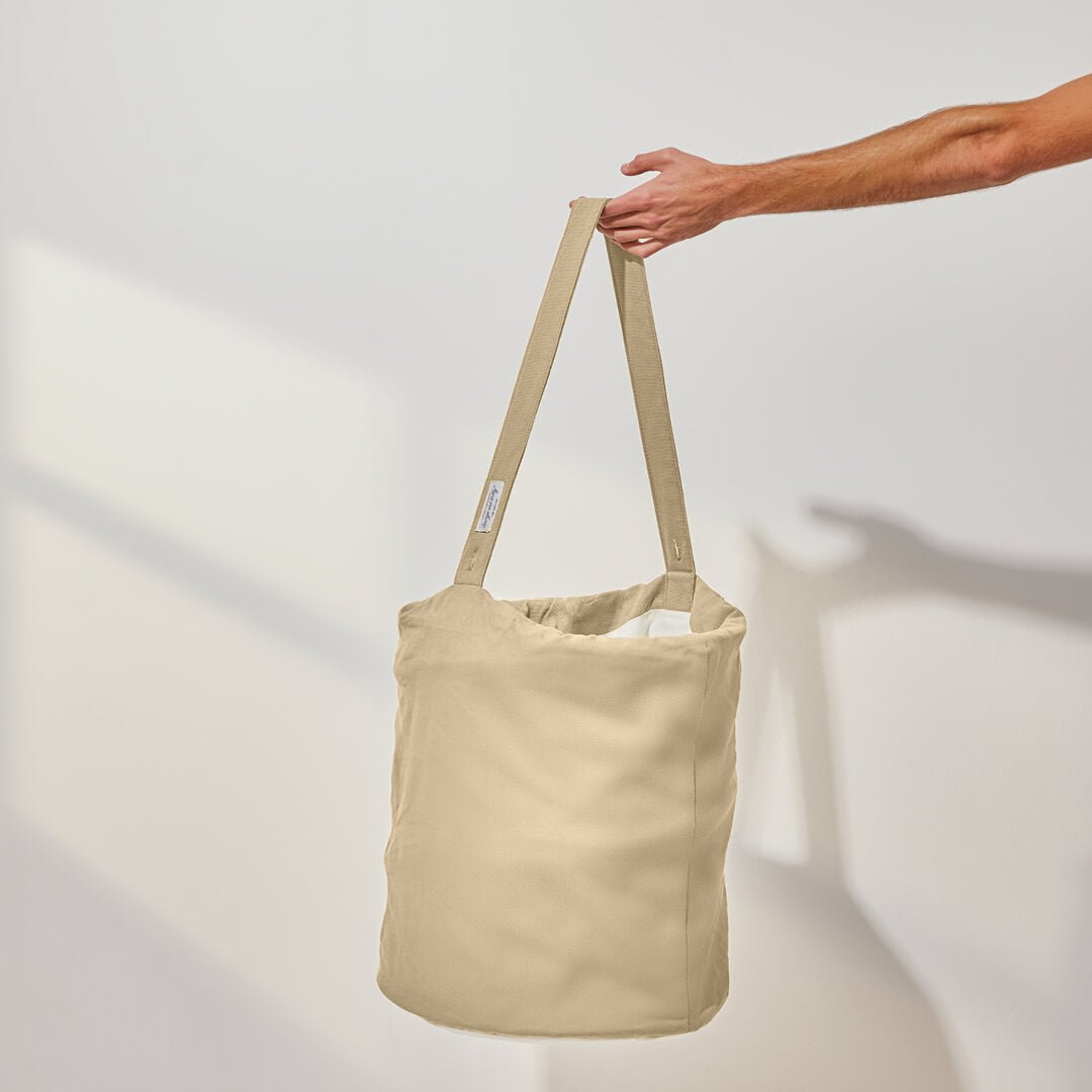 person holding the handle of the laundry hamper in oat