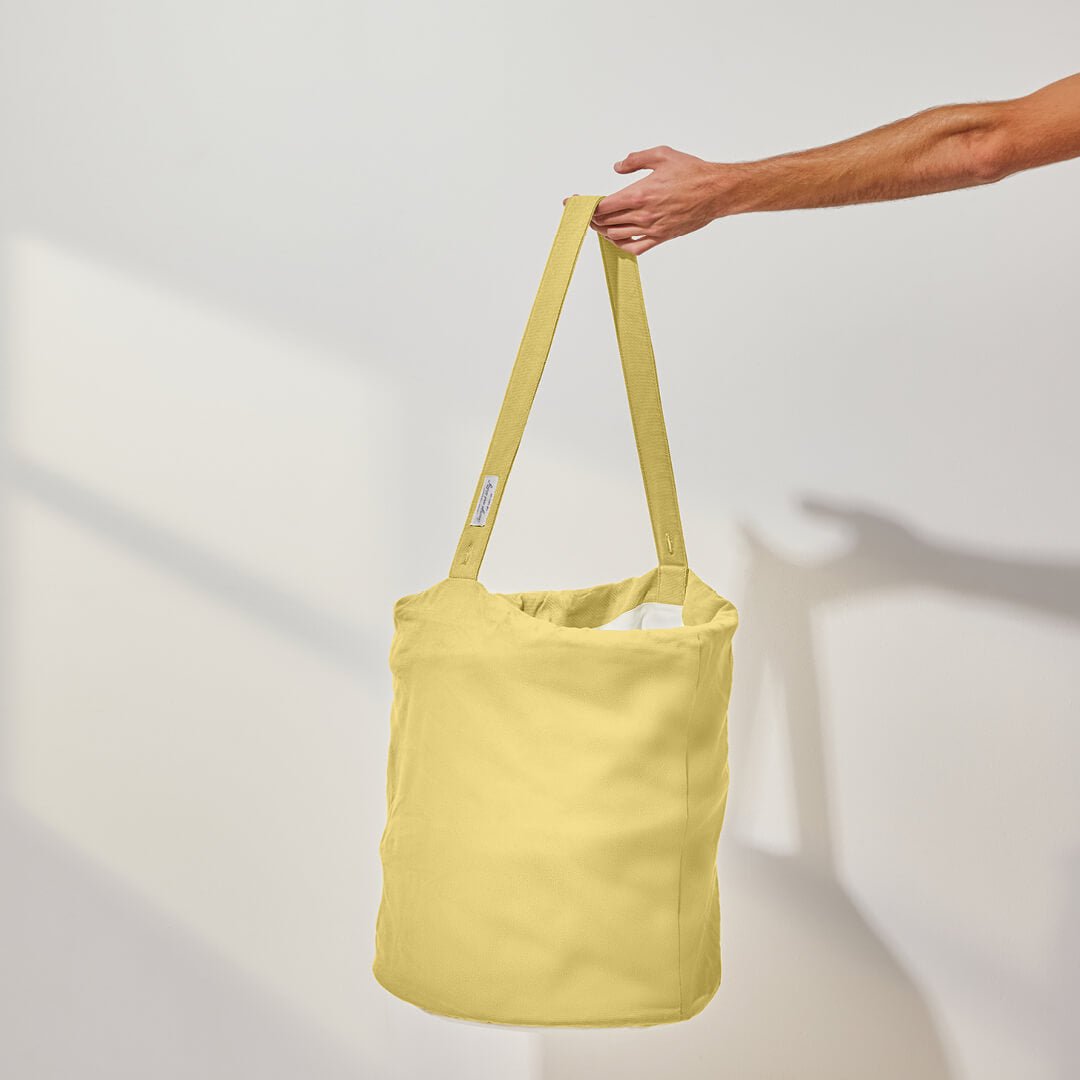 person holding the handle of the laundry hamper in yellow