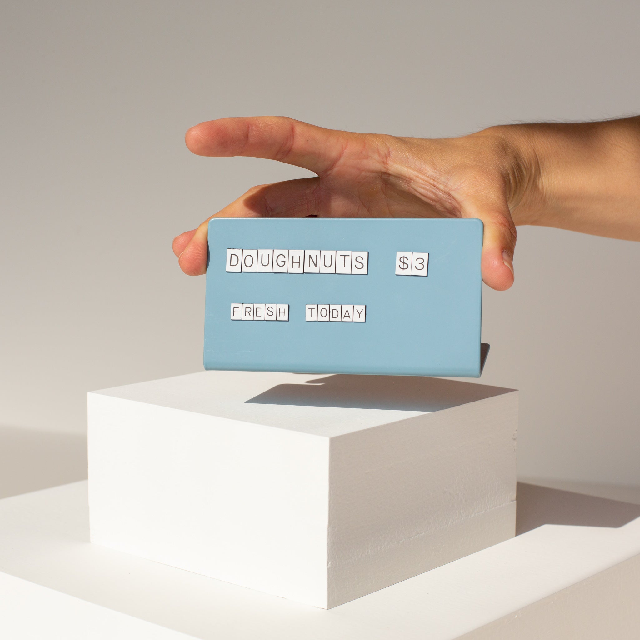 one hands picking up the blue counter sign with white magnet letters