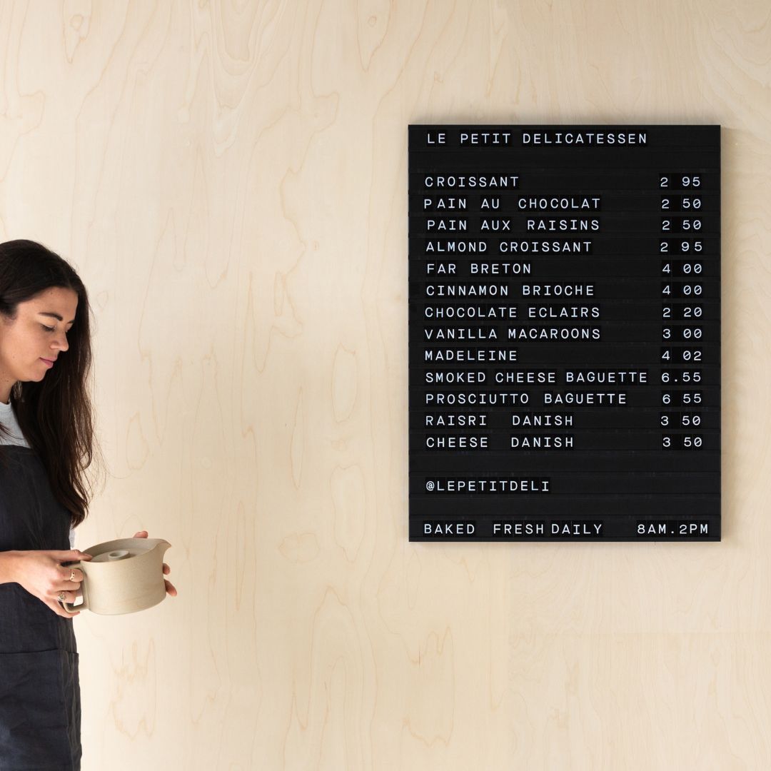 girl standing beside a black menu board installed on a retail store wall