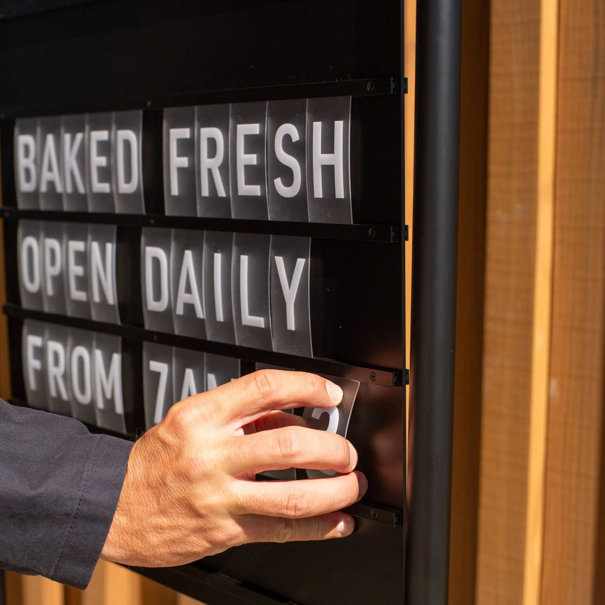 very close up of hand adjusting letters on black letter swing sidewalk sign