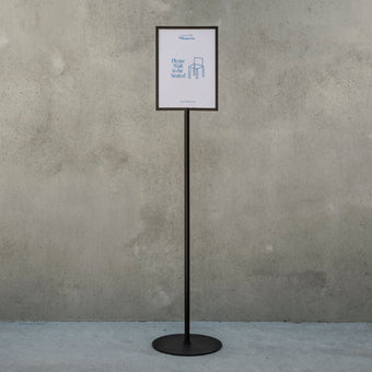black freestanding sign holder in front of a concrete wall with small poster displayed