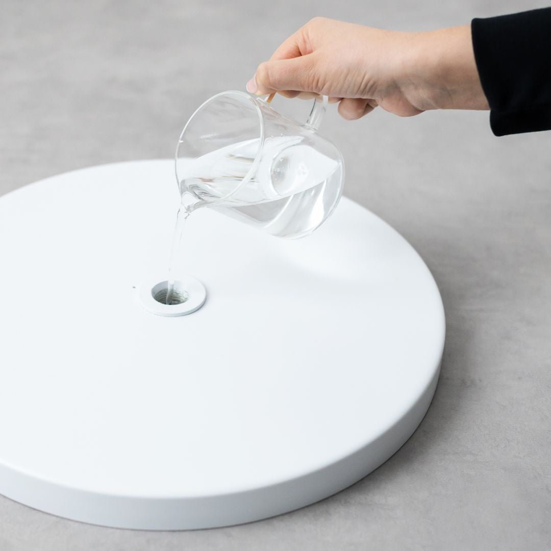 person filling the base of the standing round sign with water for weight and stability