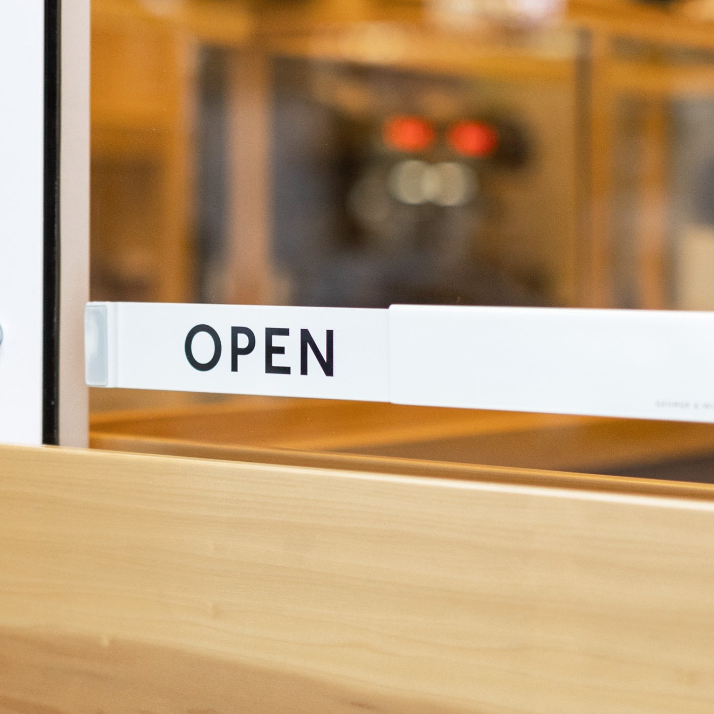 Aluminum Open Closed sign in white, mounted on glass shop door showing OPEN