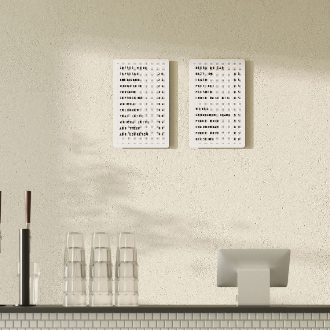 Set of two white peg letter boards with black letters, mounted vertically on café wall