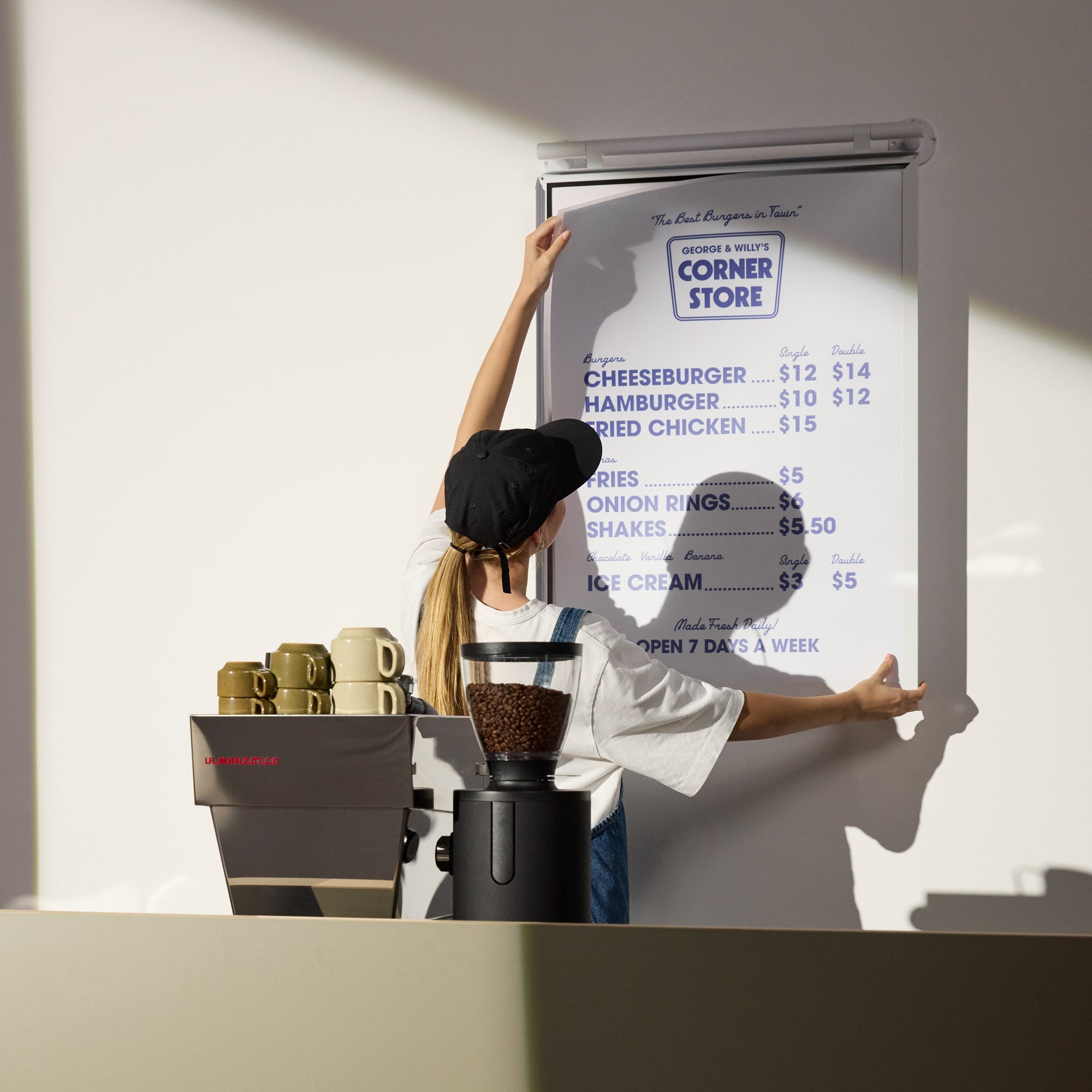 person changing poster in white poster hanging menu board behind countertop