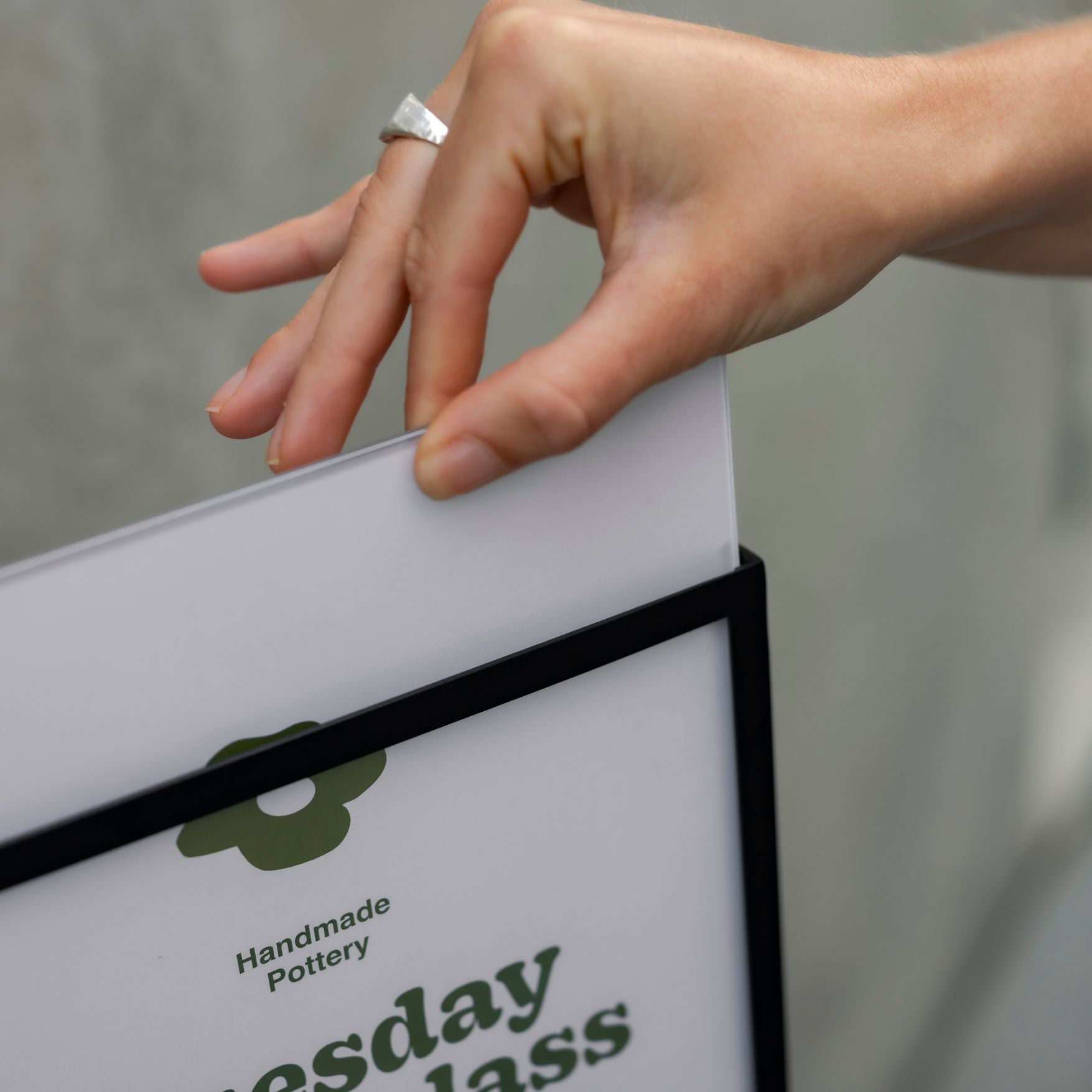 hand removing a poster from the standing sign holder showing detail