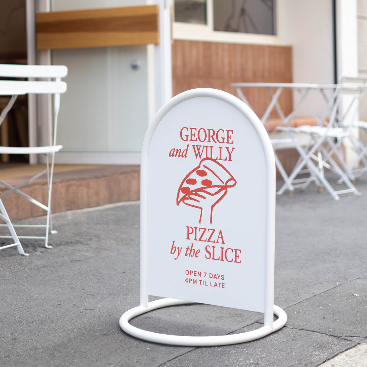 white rounded sidewalk metal sign in front of outdoor tables on a pavement