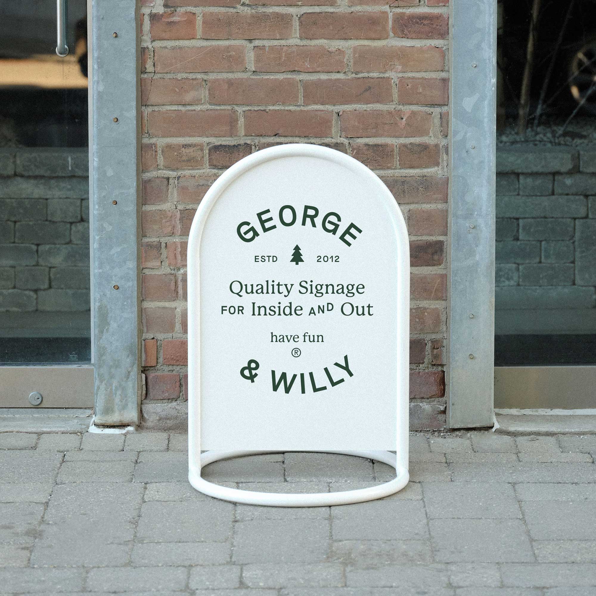 white rounded sidewalk metal signage on a pavement outside brick facade