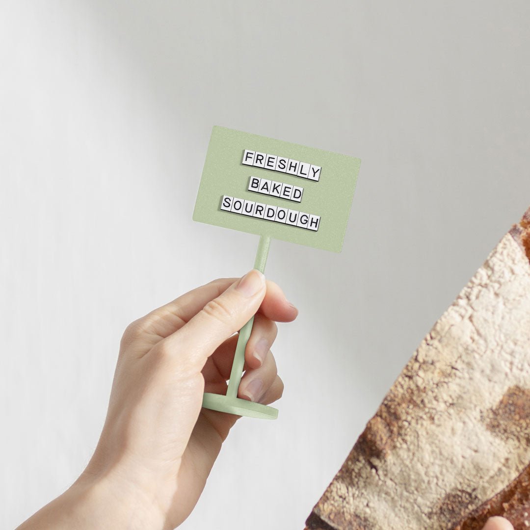 hand holding up the sage green standing counter retail sign