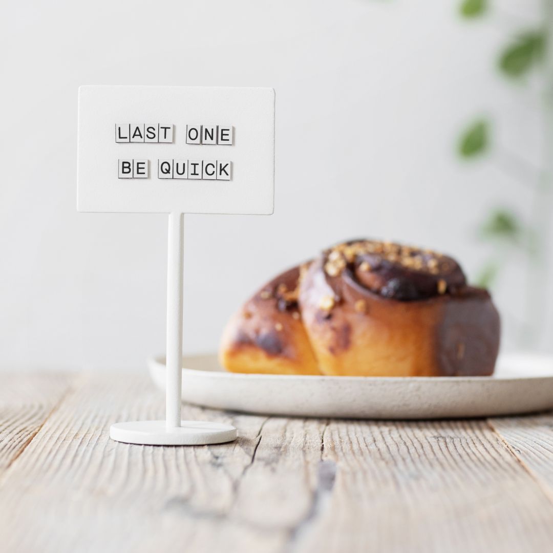 white standing magnetic counter sign in front of a pastry showing price