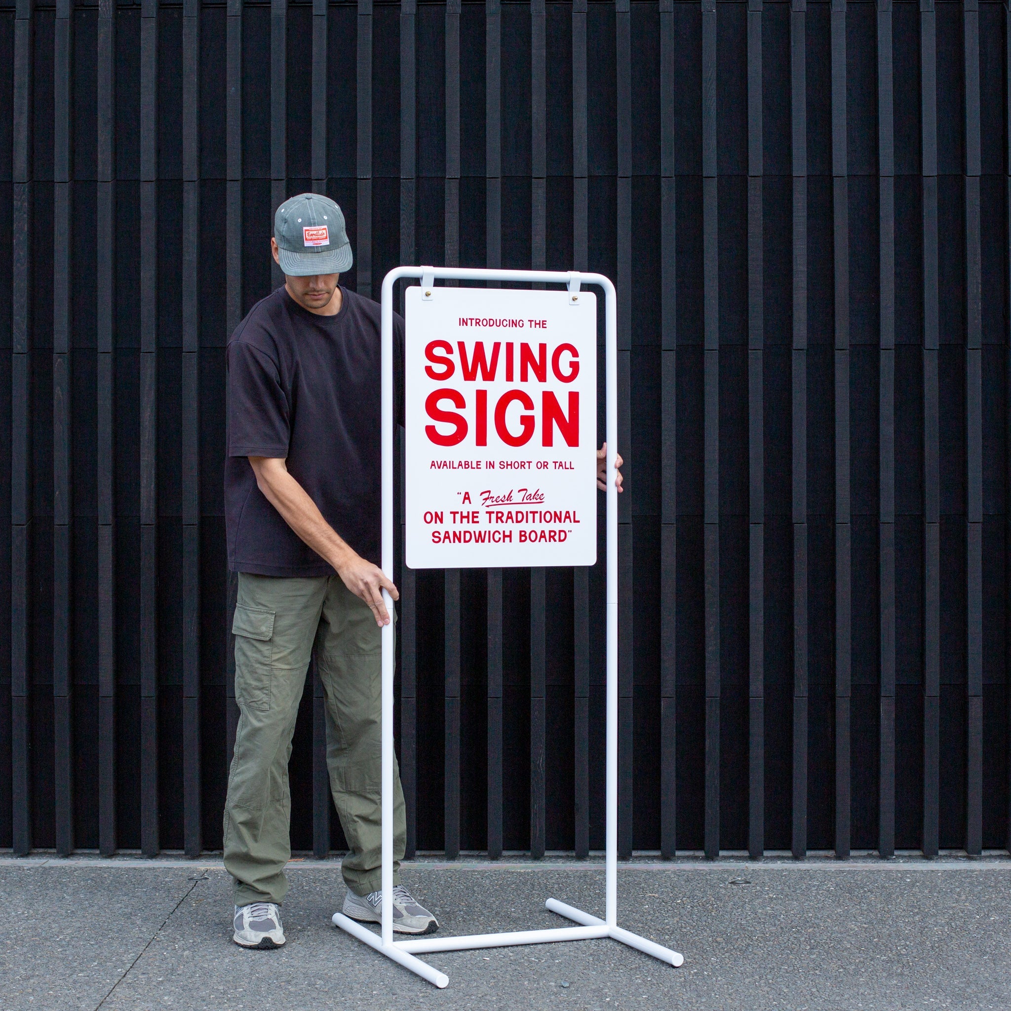 person adjusting the tall version of the swing sandwich board sign using extension rods outside on pavement