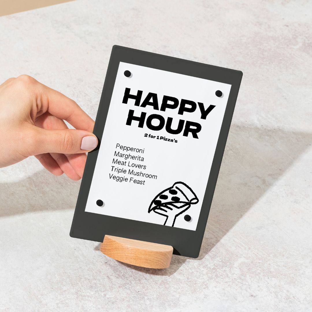 hand holding black table talker displaying happy hour specials notice