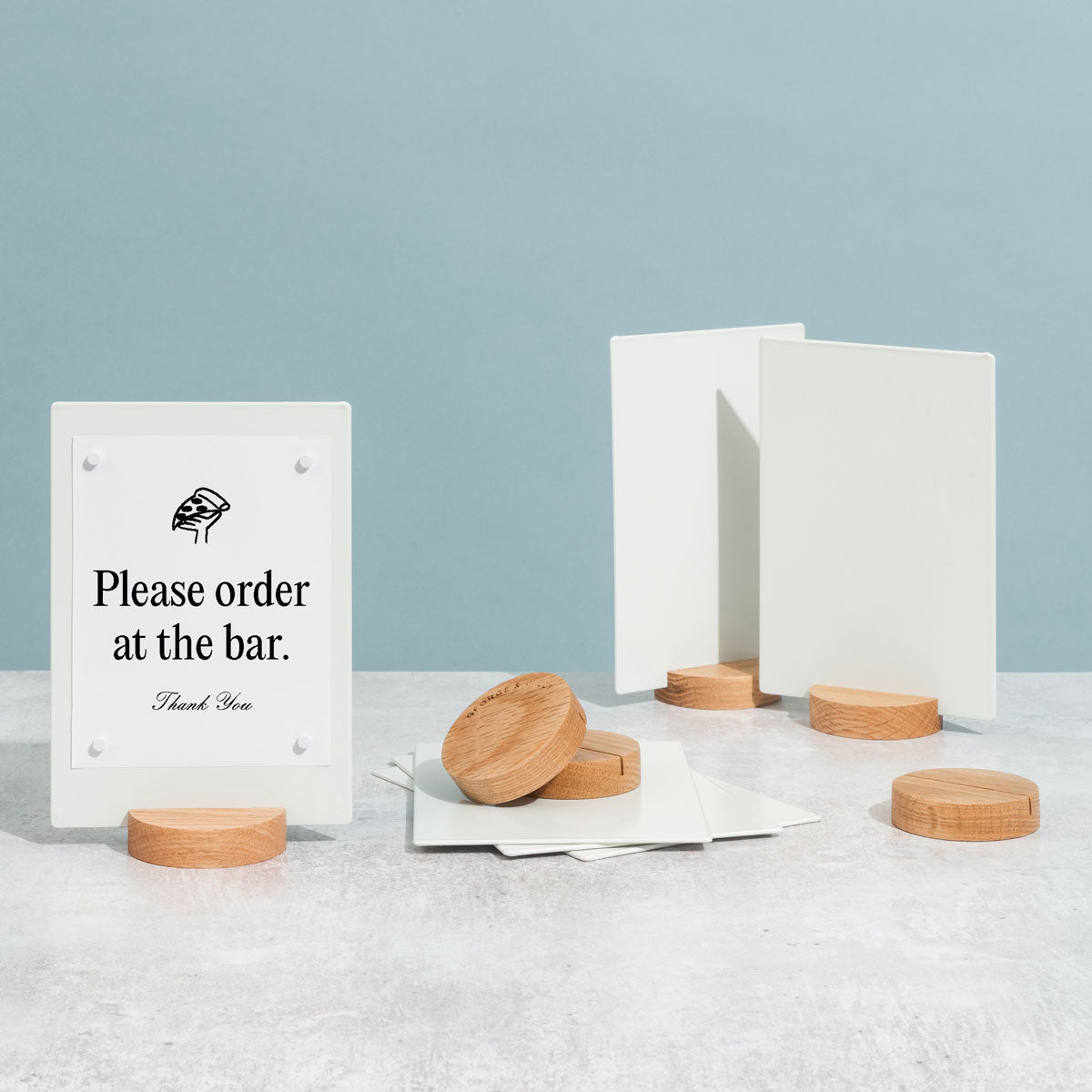 three white table talkers and extra wooden bases displayed on a tabletop