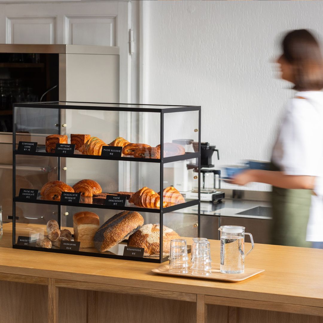 black three-tier bakery display case cabinet with pastries on display