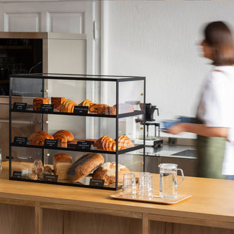 black three-tier bakery display case cabinet with pastries on display