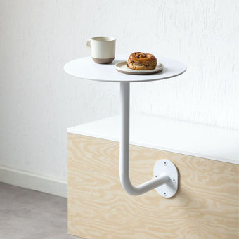 White wall-mounted cafe table with coffee and pastry on top, showcasing a compact cafe table