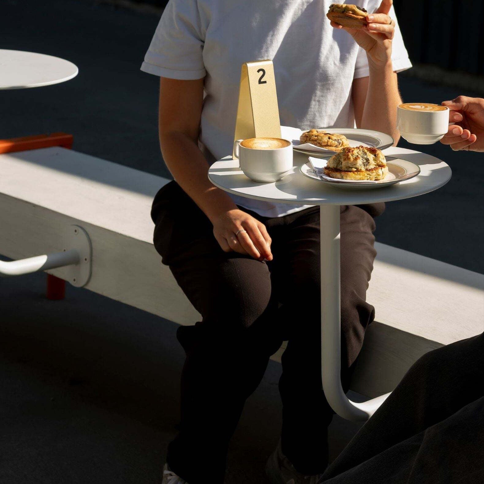 two customers seated at wall-mounted cafe table enjoying drink in minimalist café interior