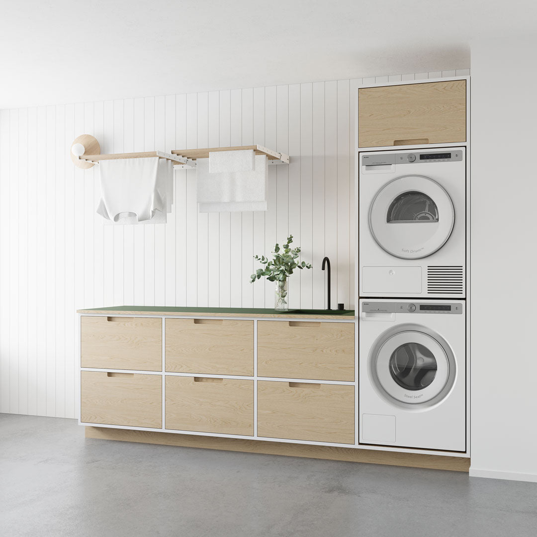 laundry space including washer, dryer and counter with wall-mounted drying rack installed above sink with clothes hanging