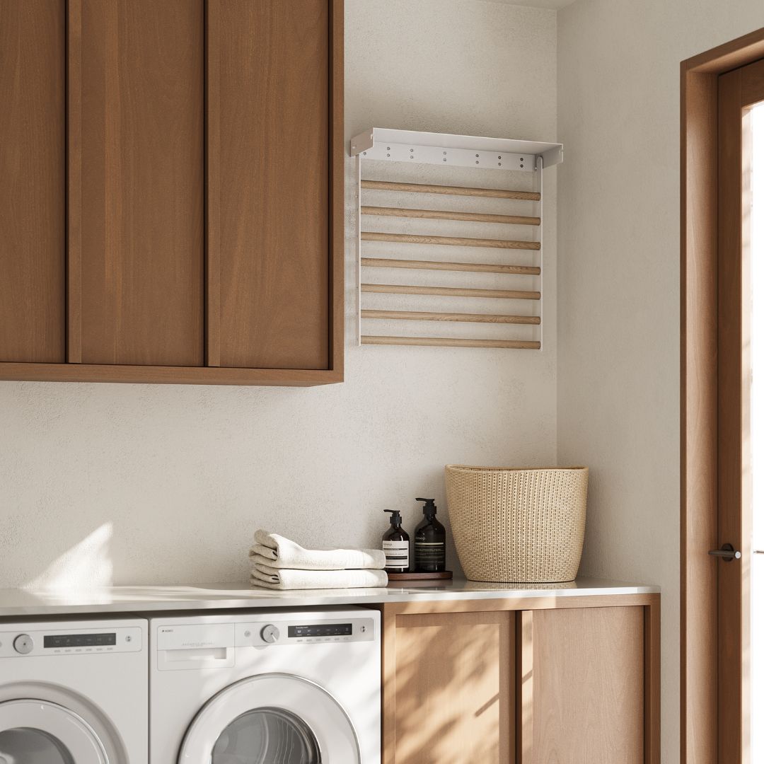 laundry space including counter and washing machine/dryer with wall mounted drying rack above the counter folded away