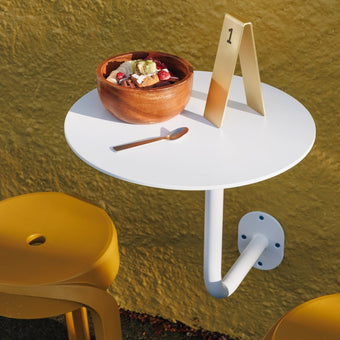white wall mounted cafe table installed outside restaurant patio with table numbers on it